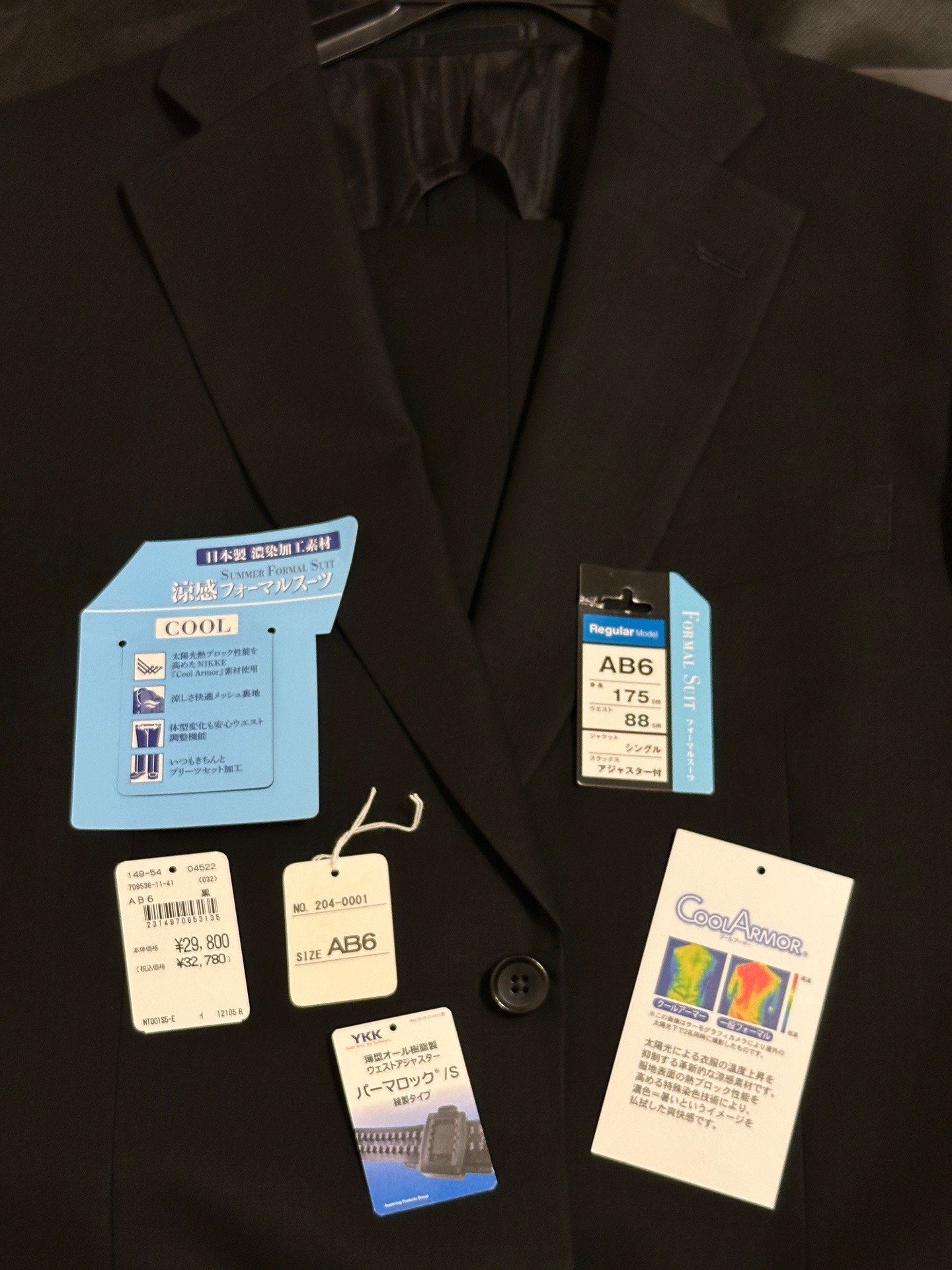 葬儀用に礼服をイオン実店舗で購入した。裾直しに1時間半ほどで税抜き350円。アプリ割引5%適用。合計で税込み27346円。 「太陽光の熱をブロックする涼感素材とメッシュ裏地で快適な着心地を実現した2ボタンスーツです。スラックスは折り目が取れにくく、ウェスト±8cmまで調節可能です。」 「品番 NT001S5-E」 「原産国 ベトナム」 「素材 表地 毛85% ポリエステル15% / 裏地 ポリエステル100%」 「洗濯方法 ドライ」 「カラー クロ/サイズ AB6」 「JANコード 2314970953135」 「商品サイズ ＜ジャケット＞着丈75cm 肩巾47.6cm 胸囲115.5cm 胴囲104cm 袖丈61cm 袖口幅15.1cm 衿幅8.2cm ＜パンツ＞ウェスト88cm 股上27.5cm 股下92cm 膝幅25.4cm 裾幅22.8cm 渡巾36.1cm」 サマー レギュラー ２ボタンシングル フォーマルスーツ メンズ 