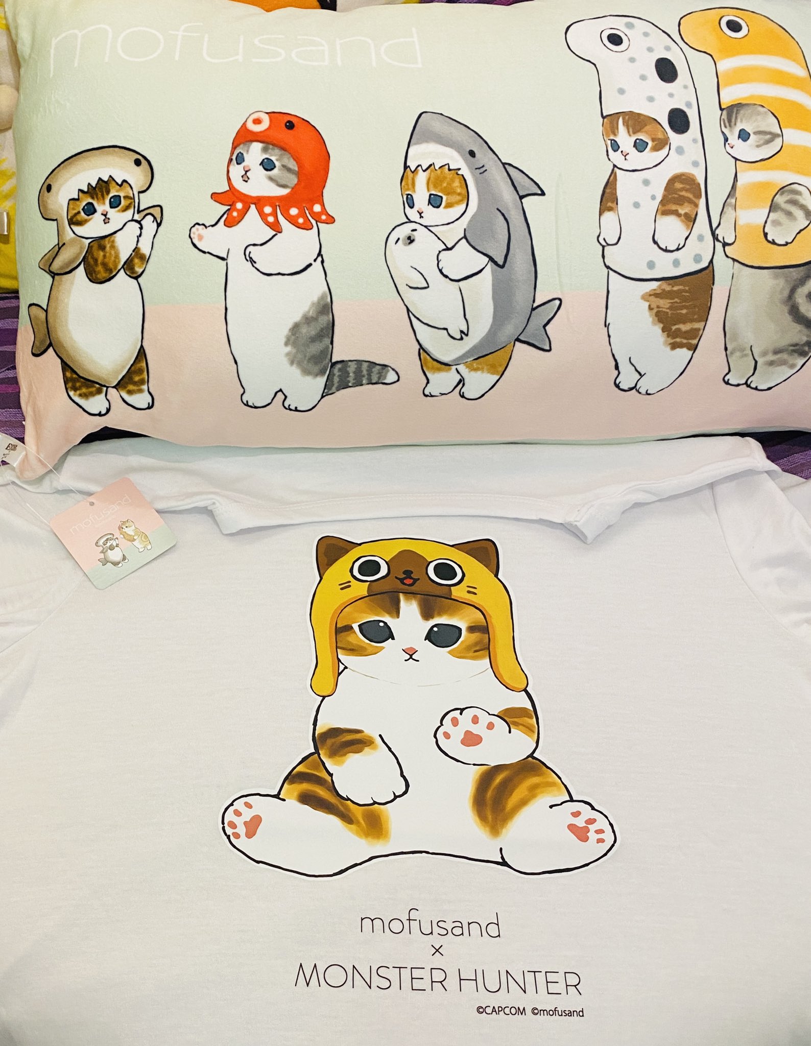 カプコン モンスターハンター × mofusand Tシャツ。アイルー。包装の袋には製品素材 ポリエステルと書かれていて、Tシャツのタグにはポリ綿と書かれている。 カプコン モンスターハンター × mofusand Tシャツ。アイルー。包装の袋には製品素材 ポリエステルと書かれていて、Tシャツのタグにはポリ綿と書かれている。